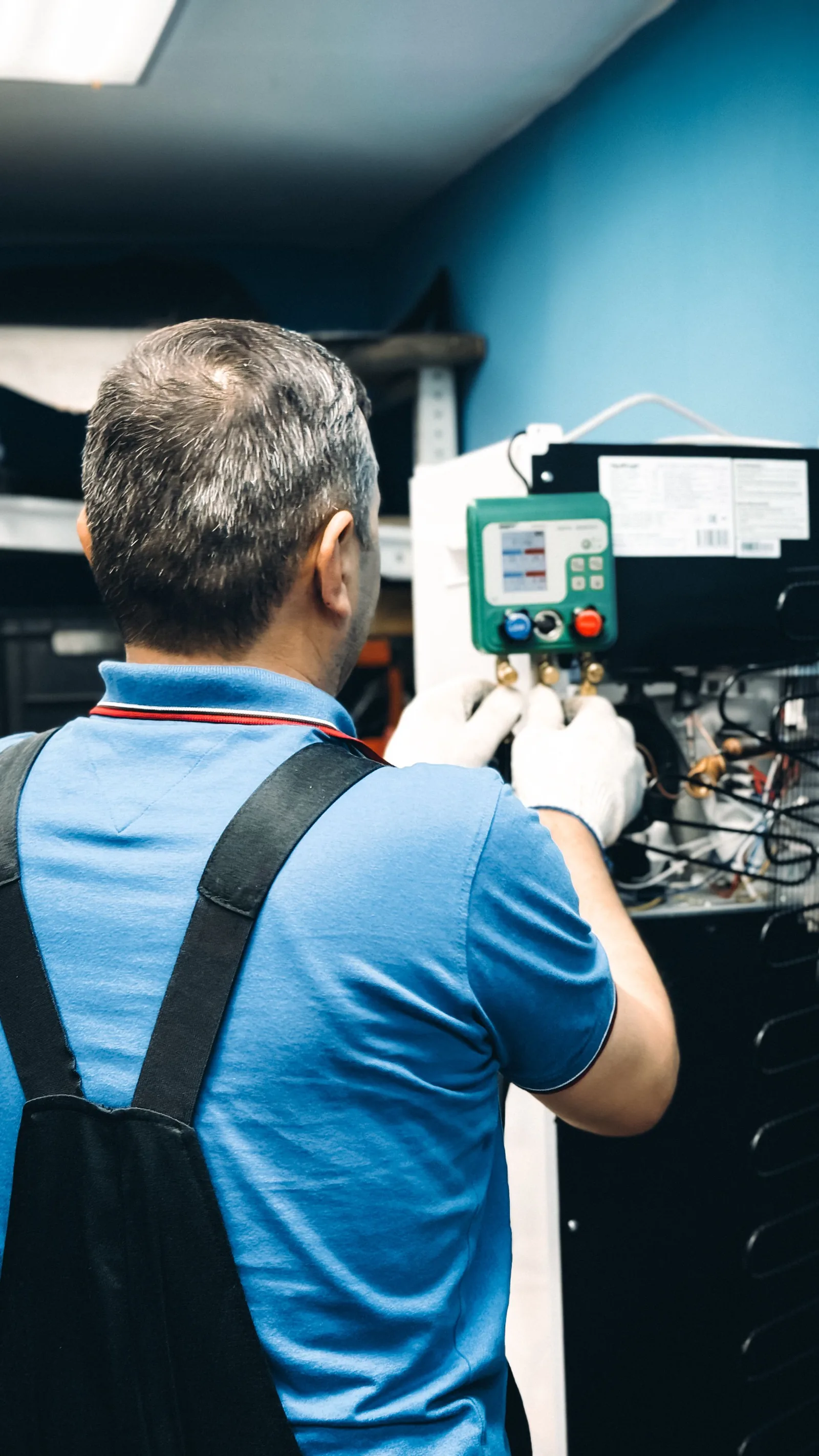 Technician servicing a commercial refrigeration unit's electronic controller and evaporator coil
